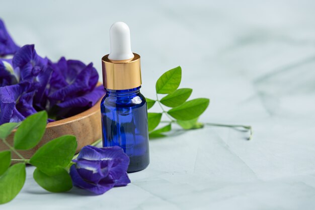 Butelka serum z olejkiem Butterfly Pea Flower nałożona na białe marmurowe tło