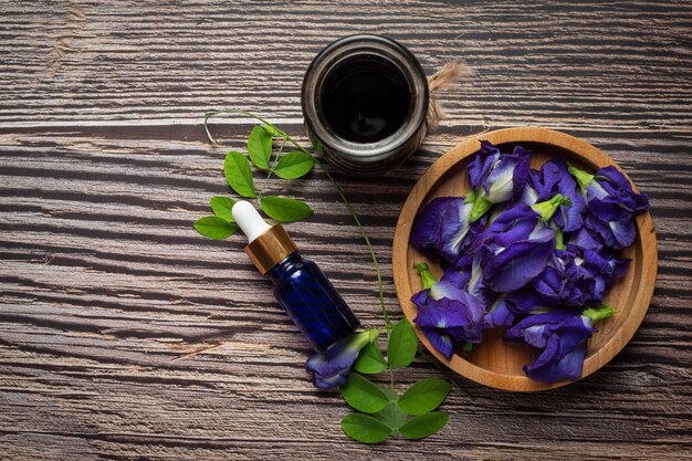 Butelka serum z olejku Butterfly Pea Flower nałożona na podłoże drewniane