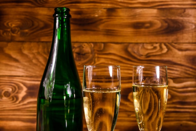 Butelka szampana i dwa kieliszki do wina na rustykalnym drewnianym stole