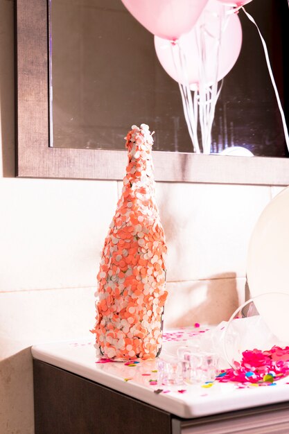Butelka szampana pokryte pomarańczowym i białym konfetti na biurku