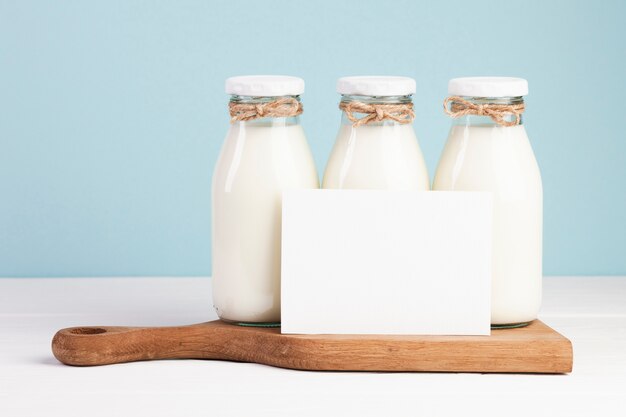 Butelki mleka i karta na desce do krojenia