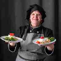 Bezpłatne zdjęcie buźka kobieta kucharz trzyma naczynia w obu rękach