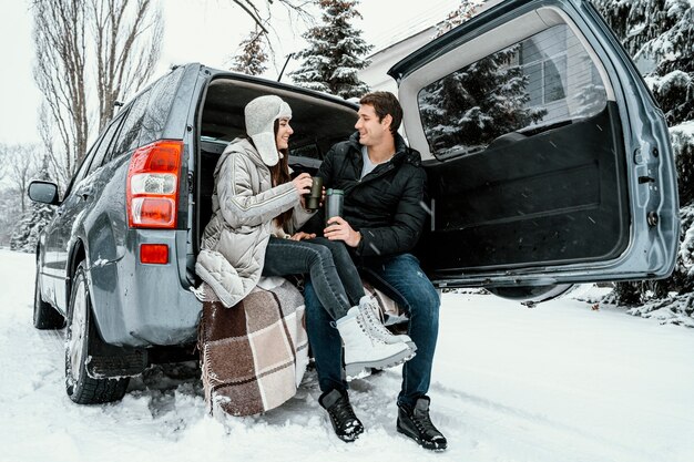 Buźka para przy ciepłym drinku w bagażniku samochodu podczas podróży