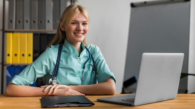 Buźka pielęgniarka w biurze ze stetoskopem i laptopem
