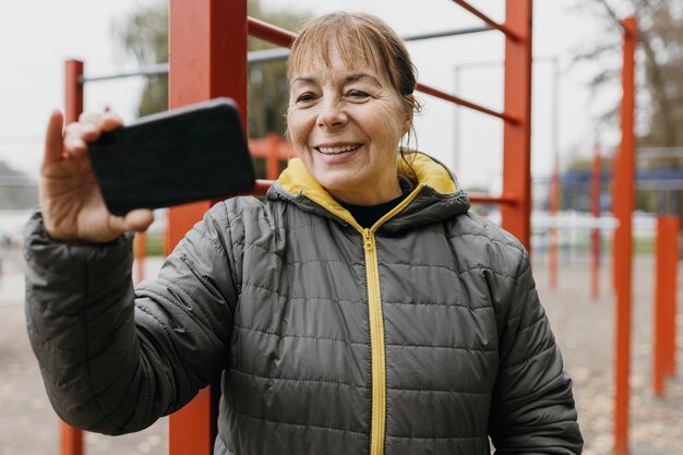 Buźka starsza kobieta ogląda wideo na swoim smartfonie