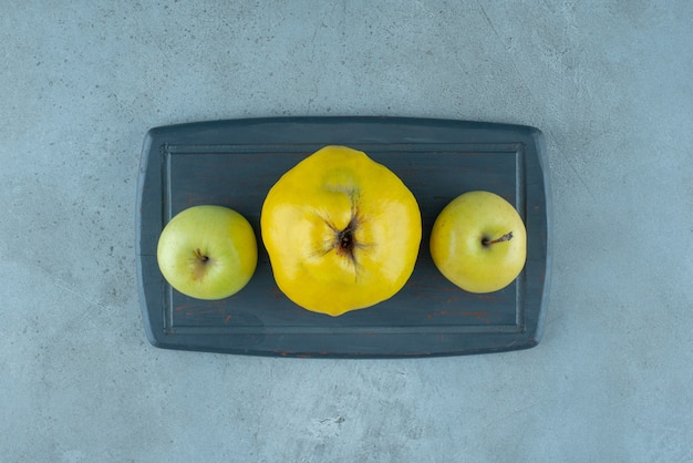 Całe jabłka i pigwa na desce, na marmurowym tle. zdjęcie wysokiej jakości