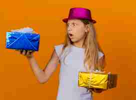 Bezpłatne zdjęcie całkiem mała dziewczynka w świątecznym kapeluszu, trzymając pudełka