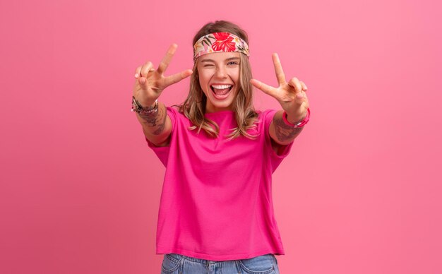 Całkiem urocza uśmiechnięta kobieta w różowej koszuli akcesoria w stylu boho hippie uśmiechnięta emocjonalna zabawa pozuje na różowym tle na białym tle pozytywny nastrój