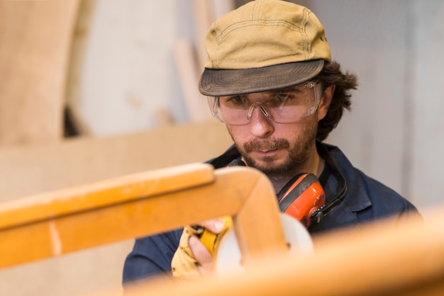 Bezpłatne zdjęcie carpenter szlifuje drewniane meble za pomocą szlifierki w warsztacie