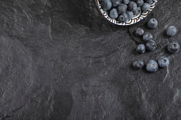 Bezpłatne zdjęcie ceramiczna miska pysznych świeżych jagód na czarnej powierzchni