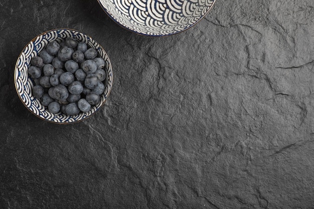 Ceramiczna miska pysznych świeżych jagód na czarnej powierzchni