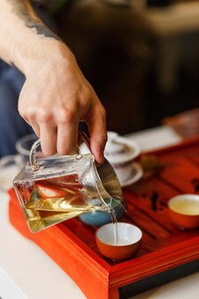 Ceremonia parzenia herbaty. ręce człowieka nalewania herbaty w misce herbaty. zbliżenie.