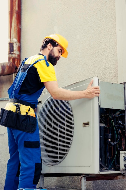 Bezpłatne zdjęcie certyfikowany technik zatrudniony do naprawy uszkodzonego klimatyzatora, demontażu przedniego panelu cewki kondensatora w celu sprawdzenia uszkodzonych elementów wewnętrznych.