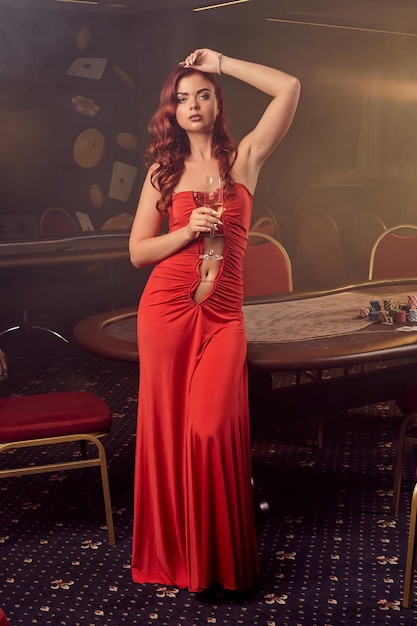Bezpłatne zdjęcie charnimg sexy kobieta pozuje przy stole pokerowym w luksusowym kasynie.