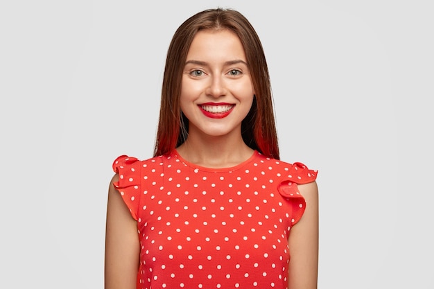 Bezpłatne zdjęcie charyzmatyczna kobieta z czerwoną szminką pozuje na białej ścianie