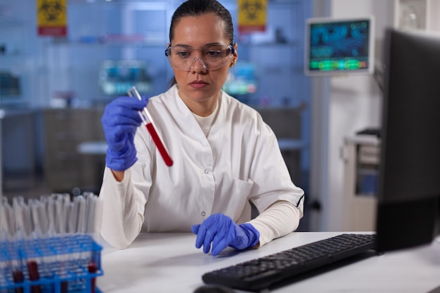 Chemik naukowiec trzymający probówki z krwią pacjenta, pracujący w diagnostyce chorób w biochemicznym laboratorium szpitalnym. Lekarz opracowujący medyczną szczepionkę przeciwko Covid19 podczas eksperymentu chemicznego