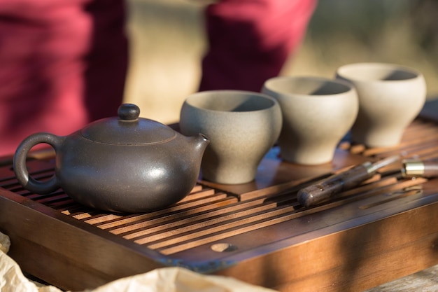 Chińska Ceremonia Parzenia Herbaty. Czajnik Ceramiczny Wykonany Z Gliny I Misek Na Drewnianym Tle. Premium Zdjęcia