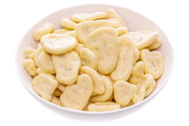 Chipsy bananowe w białej czekoladzie, w białym talerzu na białym tle, pojedyncze produkty
