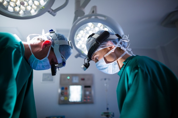 Chirurdzy noszący chirurgiczne lupy podczas wykonywania operacji