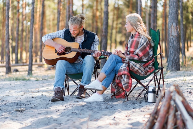 Chłopak gra na gitarze akustycznej na zewnątrz