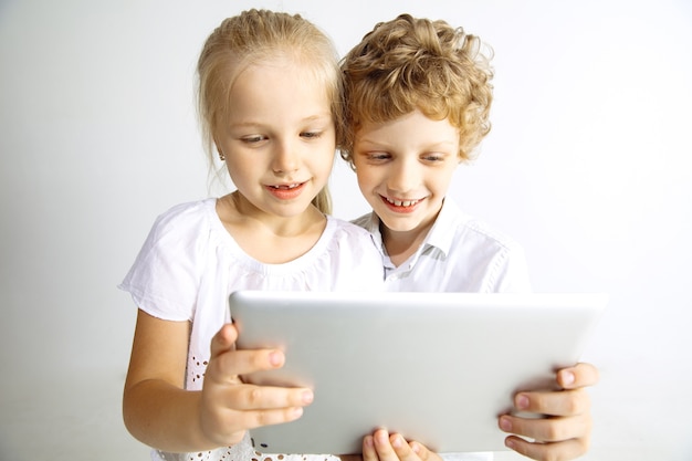 Chłopak i dziewczyna w dżinsach, najlepsi przyjaciele lub brat i siostra bawią się. Robienie selfie na tablecie. Koncepcja dzieciństwa, edukacji, wakacji lub pracy domowej, nowoczesne technologie.