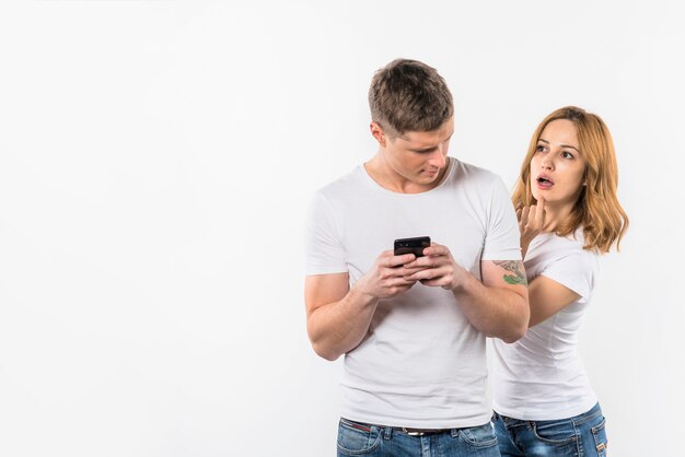 Bezpłatne zdjęcie chłopak patrzeje jej dziewczyny skrycie patrzeje w telefonie komórkowym