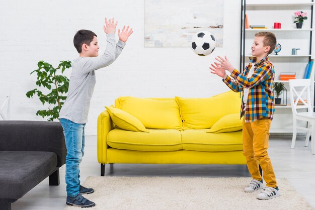 Chłopcy grają w piłkę nożną w salonie