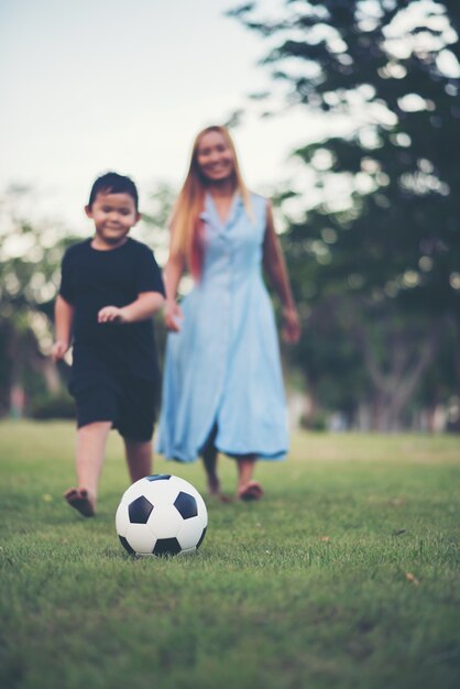 Chłopiec bawić się piłka nożna futbol z matką w parku