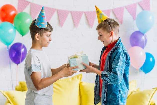 Chłopiec dając prezent urodzinowy do swojego przyjaciela