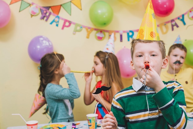 Chłopiec dmuchanie noisemaker na przyjęciu urodzinowym