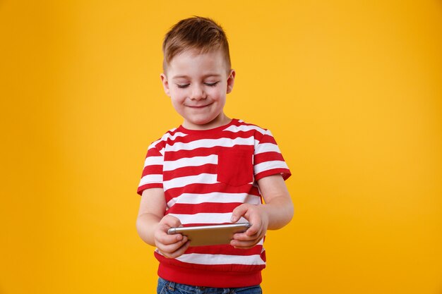 Chłopiec gra w gry lub surfuje po Internecie na cyfrowy smartfon