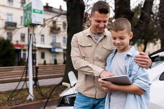 Bezpłatne zdjęcie chłopiec i tata w pobliżu elektrycznego samochodu