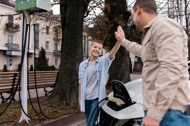 Bezpłatne zdjęcie chłopiec i tata w pobliżu elektrycznego samochodu