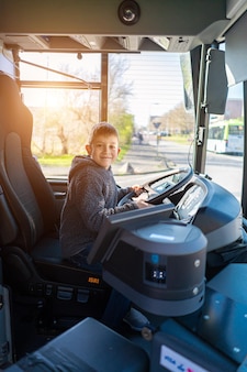Chłopiec jedzie autobusem chłopiec kręci kierownicą w porzuconym autobusie chłopiec bawi się w autobusie