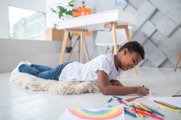 Chłopiec malujący leżący na dywanie na podłodze