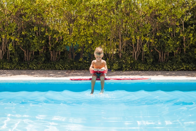 Bezpłatne zdjęcie chłopiec siedzi przy basenie z książką