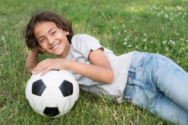 Chłopiec siedzi w trawie z piłki nożnej
