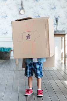 Chłopiec stojący z kartonu na głowie z narysowanego robota