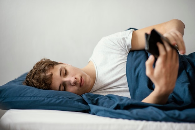 Chłopiec w łóżku z telefonem komórkowym