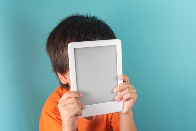 Chłopiec w pomarańczowej koszulce trzymający czytnik ebooków