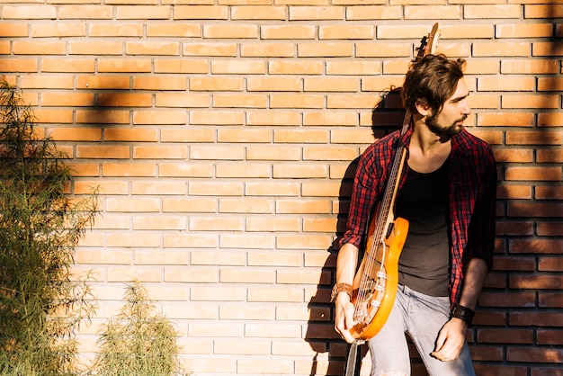 Chłopiec z gitarą elektryczną ściana z cegieł