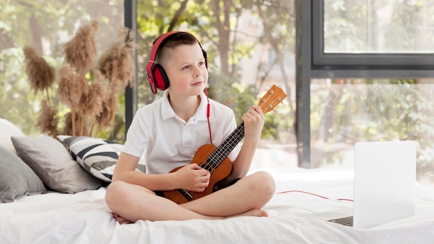 Chłopiec z hełmofonami bawić się ukulele strzał w dal