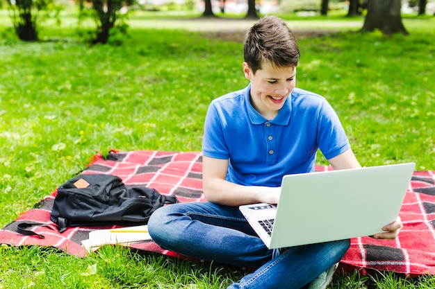 Chłopiec z laptopem w parku