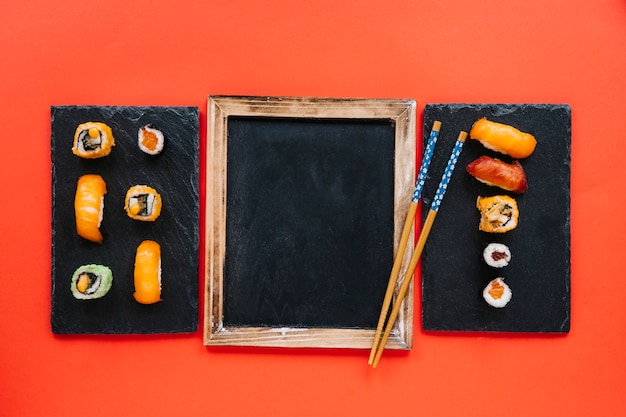 Bezpłatne zdjęcie chopsticks na blackboard między suszi deskami