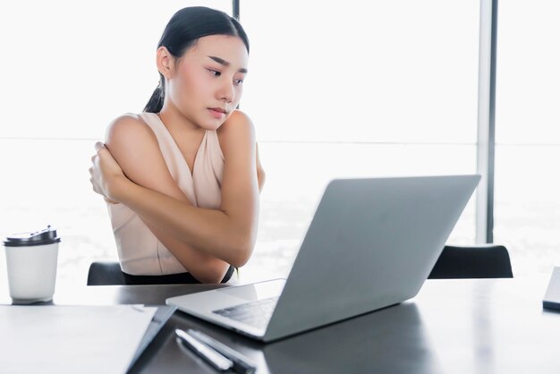 Chora azjatycka kobieta biurowa zły stan zdrowia z zespołem biurowym podczas pracy z laptopem w biurze