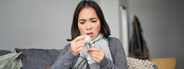 Bezpłatne zdjęcie chora koreańska kobieta patrzy na termometr z zaniepokojoną twarzą i łapie przeziębienie, mając gorączkę i covid