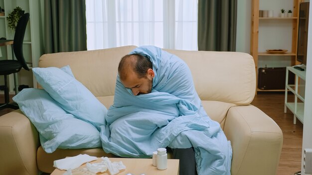 Chory człowiek owinięty kocem podczas epidemii chrząszczy.