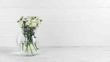 Bezpłatne zdjęcie chryzantema kwitnie wśrodku szklanego dzbanka przeciw białemu drewnianemu tłu