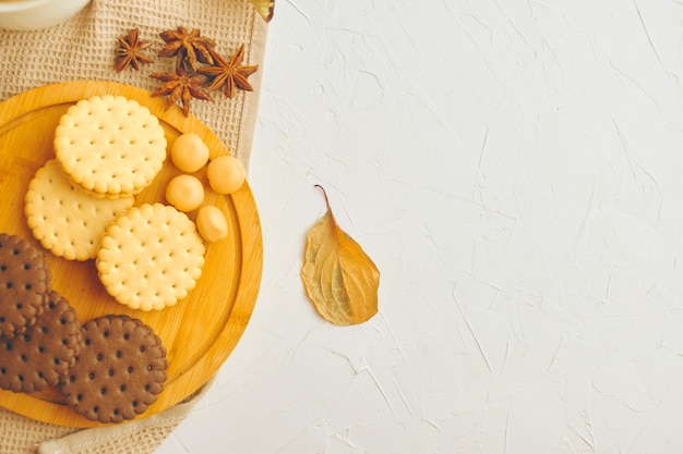 Ciasteczka i cukierki na drewnianej tacy biały stół z obrusem kuchennym słodycze i anyż jesienny le...