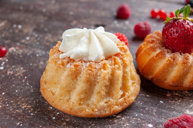 ciasteczka z truskawkami i śmietaną na brązowym, owocowym ciastku z jagodami